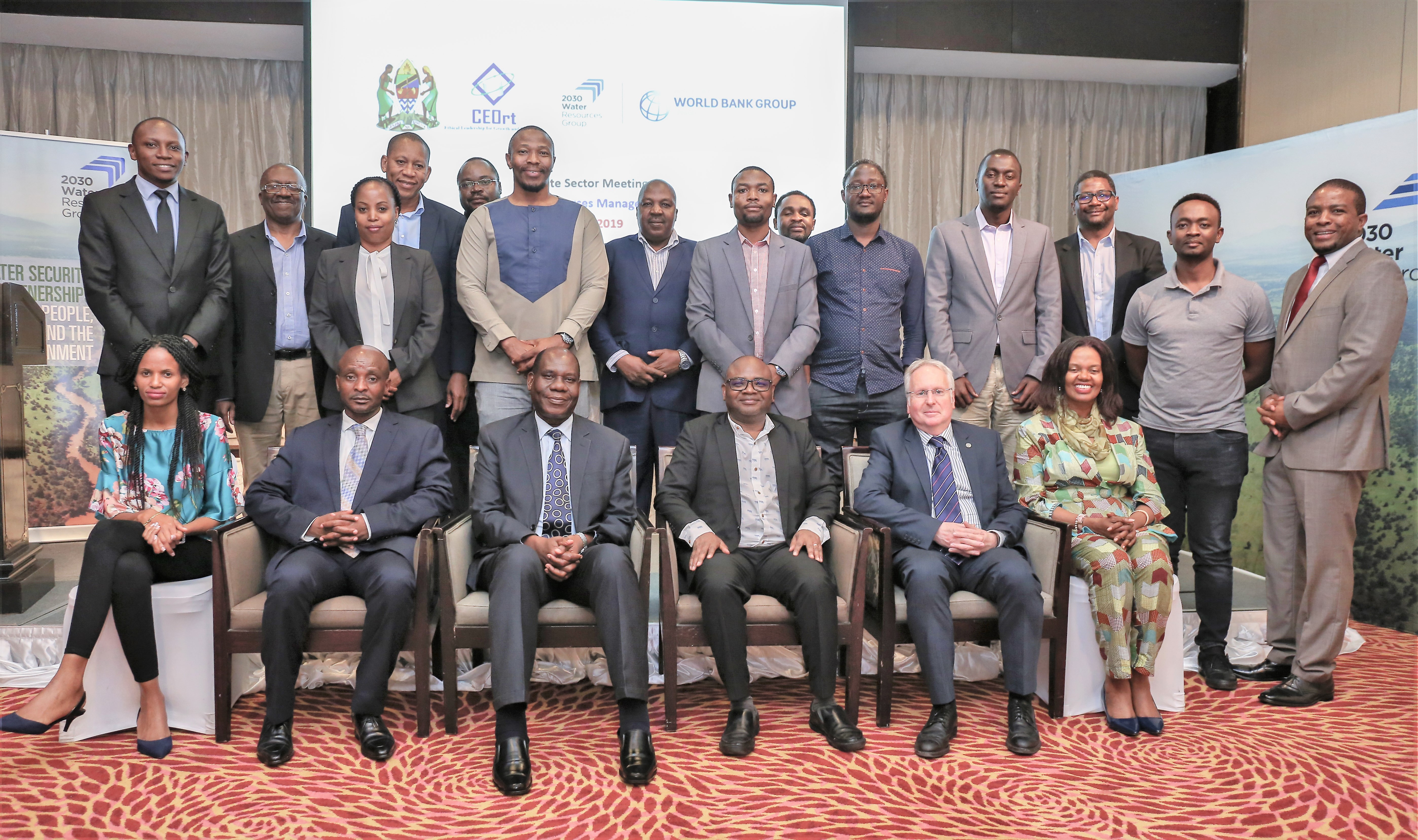 Group photo of conference participants, with event branding in the background.