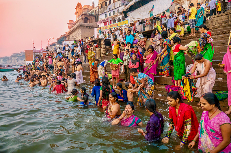 Hindu religious ritual of bathing and colorful traditional clothing in the Ganges River from the ghats of Varanasi, India.