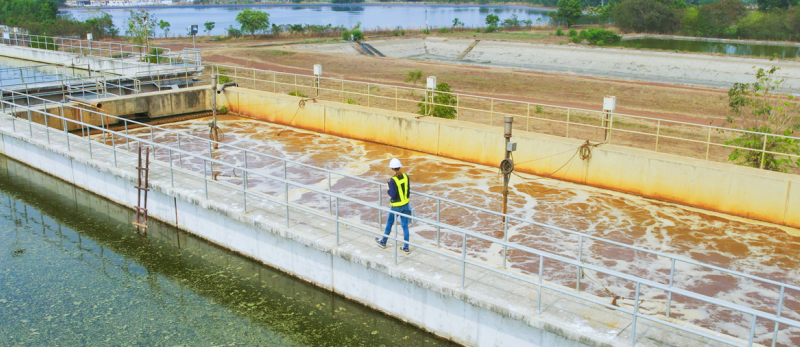 Aerial view of wastewater treatment facility with an engineer working on-site.